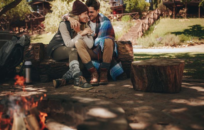Romantic couple sitting near bonfire at campsite