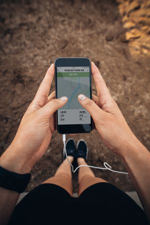 Close up POV shot of female runner using a fitness app on her mobile phone