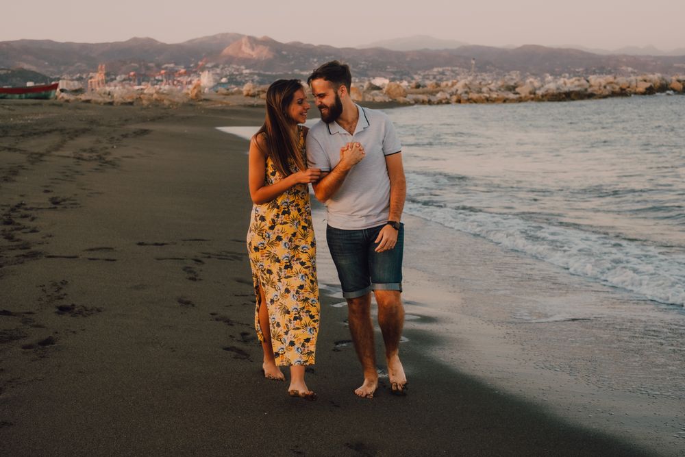 Lovely couple walking holding hands on sandy beach