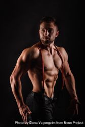 Bodybuilder practicing side poses ahead of competition in dark studio beD6N4