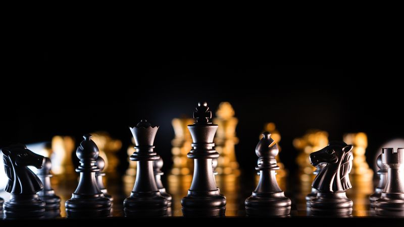Silhouetted chess pieces on illuminated board
