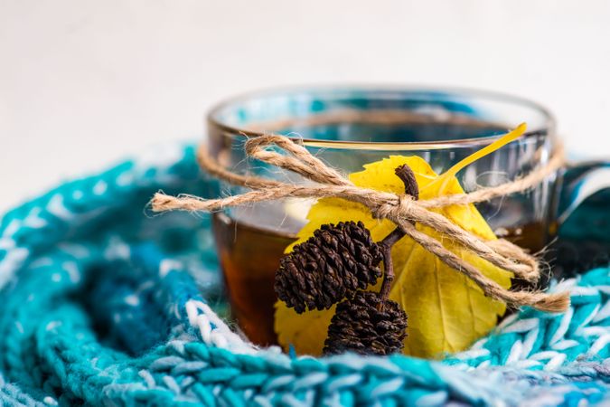 Side view of tea with lemon decorated with pine cones wrapped in blue scarf