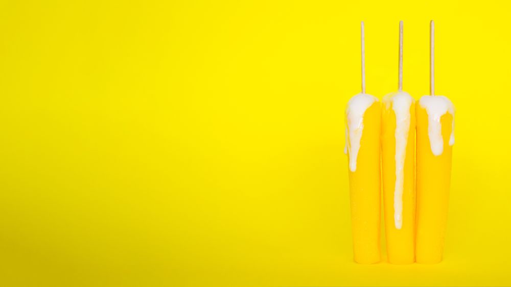 Three yellow ice pops on yellow background
