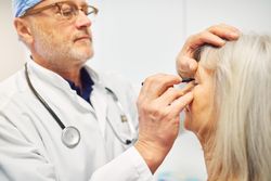 Male doctor drawing lines on a patient’s face for surgery