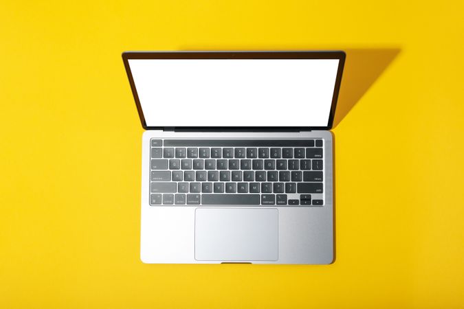 Top view of open laptop with mock up screen on yellow desk