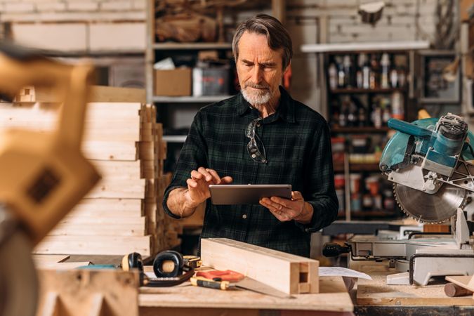 Bearded male in woodworking studio using tablet