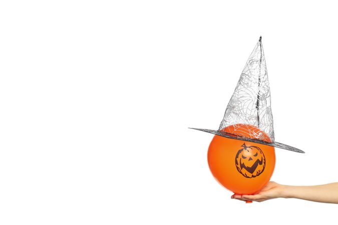 Female hand hold halloween balloon with witch hat, isolated on blank background