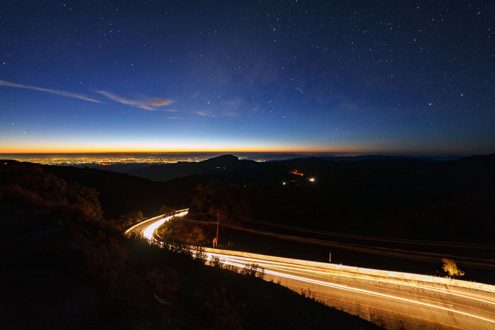 Milky way galaxy with stars and space dust in the universe and lighting on the road before morning at Doi inthanon Chiang mai, Thailand