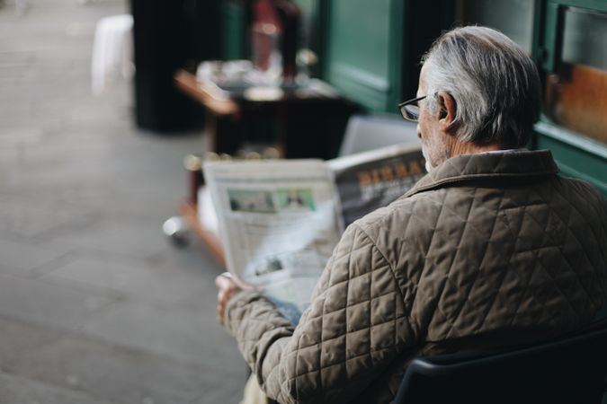 Back view of older man reading newspaper