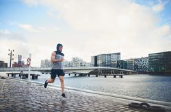 Man in vest running outside near river
