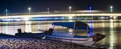 Boats on beach against glowing bridge in night