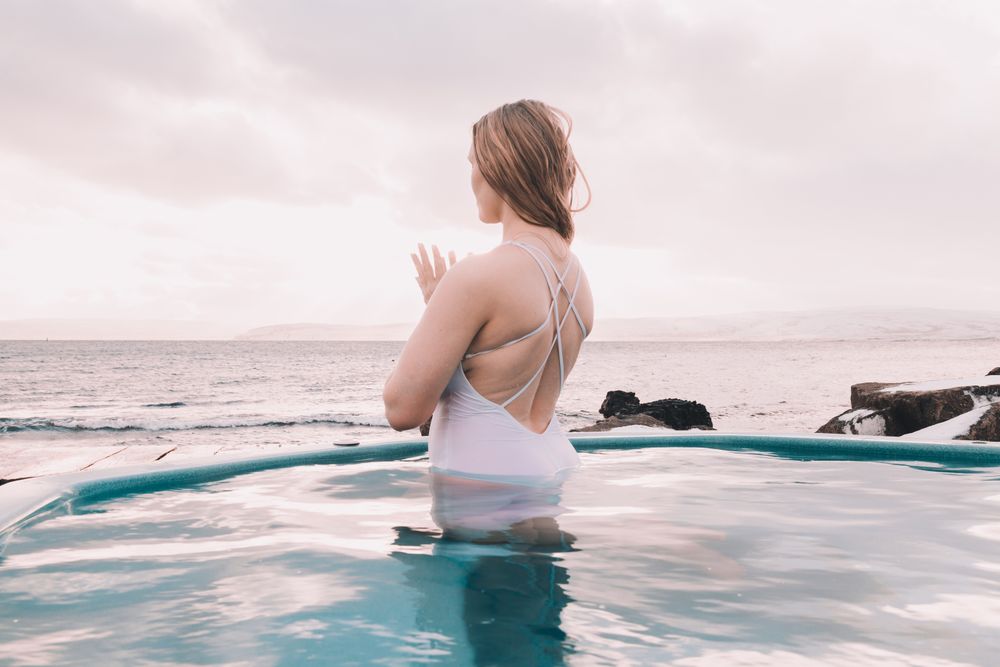 Woman sitting in pool near stones
