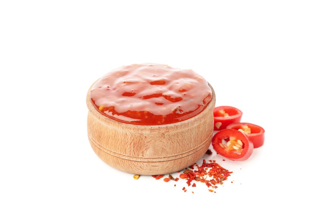Chilli pepper and bowl of sauce isolated on plain background
