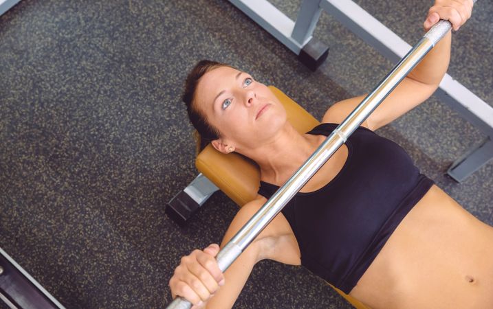 Close up looking down at woman doing bench press in gym