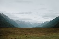 Valley with yellow grass and rocky mountains with snow