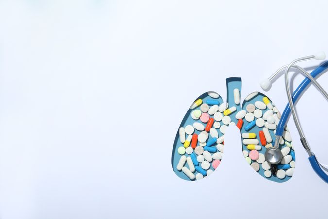Cut out lung shape with pills underneath with doctor’s stethoscope and copy space