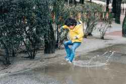 Happy kid jumping on puddle