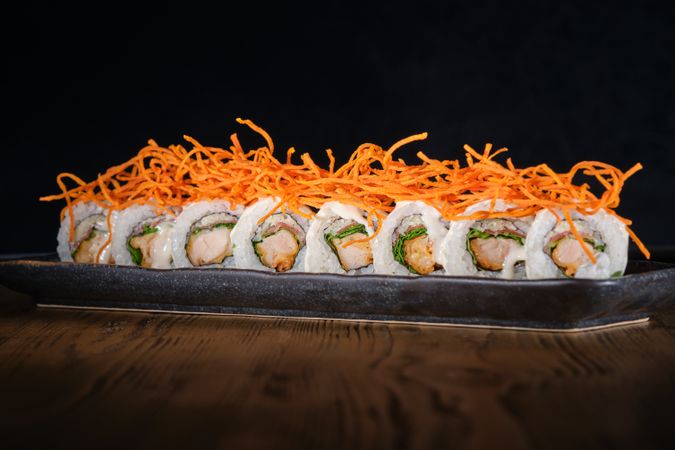 Row of sushi maki with salmon decorated with shredded carrot served on plate