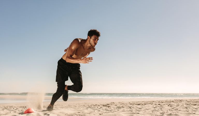Man running sprints at a beach on a sunny day