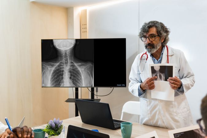 Mature doctor discussing x ray with colleagues in hospital