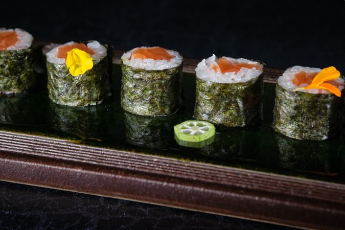 Delicious sushi rolls with salmon served on wooden tray