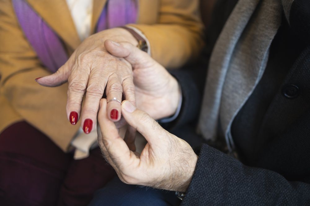 Older man putting engagement ring on his female partner