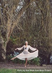 Woman in ballerina pose under tree 4BRr34