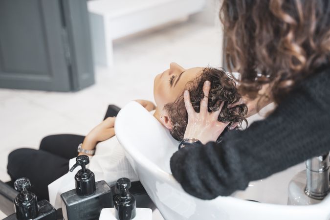 Stylist washing hair of client