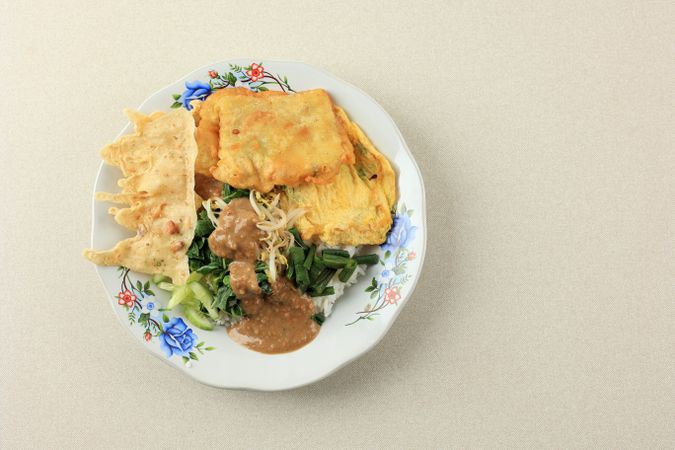 Top view of plate of Indonesian food served with peanut sauce