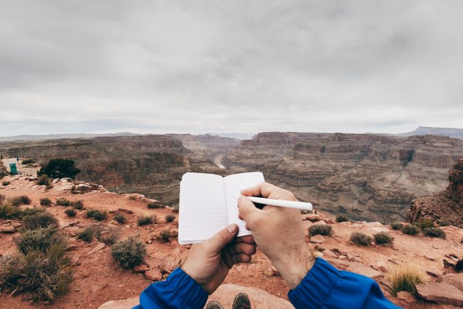 Male drawing in notebook at rock