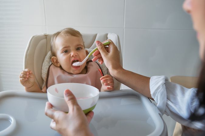 Crop mother feeding baby with spoon