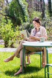 Calm pregnant young woman reading newspaper outside