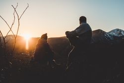 Man and woman enjoying sunset in autumn mountains