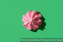 Pink meringue cookie minimalist on a green background, top view 4maW74