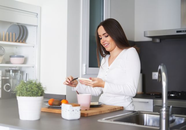 Smiling woman making sandwiches in kitchen