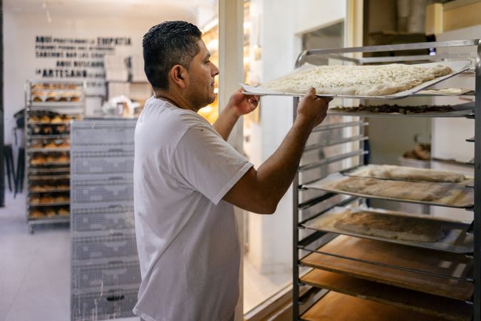 Baker placing focaccia on a tray