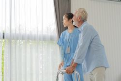 Nurse helping older male patient with walker