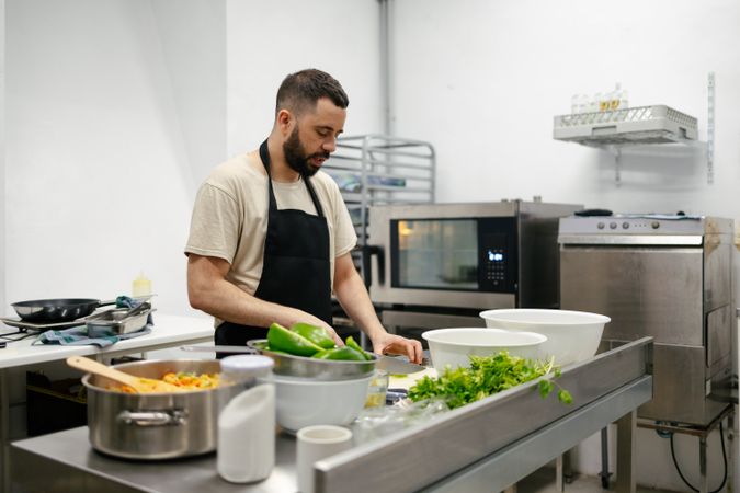 Young chef cutting peppers