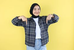 Excited Indonesian  Asian Hijab Young Woman with Casual Outfit Pointing at the Copy Space Below