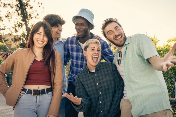 Energetic group of diverse friends having fun and celebrating together outdoors.