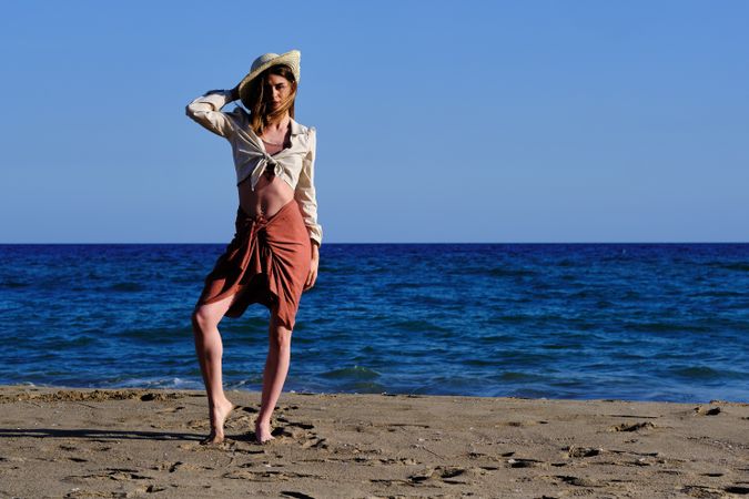 A fashion model with a hat at the beach before sunset