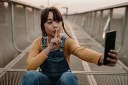 Funny girl taking selfie on smartphone on walkway