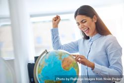 Woman with finger on globe with one fist up in celebration 0vZeg0