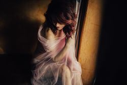 Sensual woman under veil near window