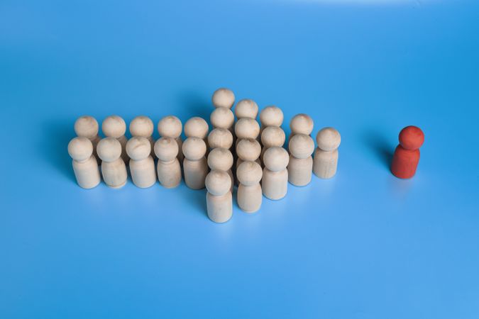 red wooden figure and wooden group crowd making arrow form. isolated on blue background. leadership and teamwork concept