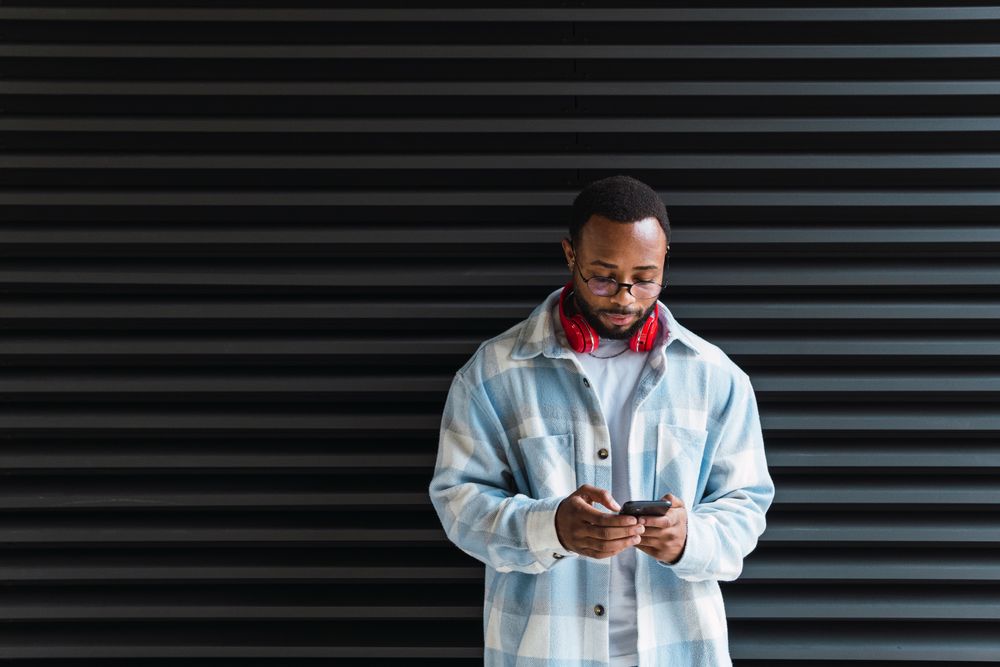 Cheerful Black man with smartphone listening to music