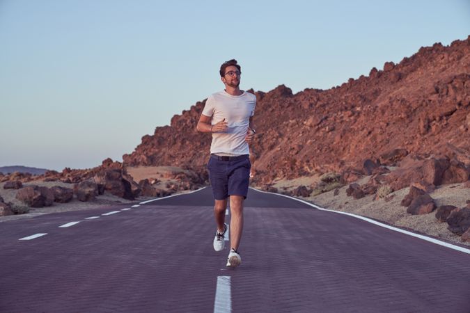 Man running on road near mountains