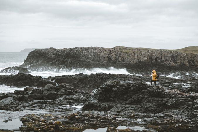 Man standing on rock and taking picture of sea