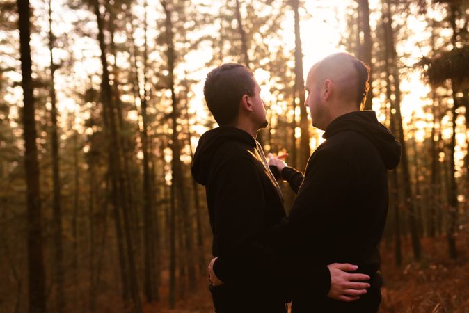 Men hugging in forest at sunset