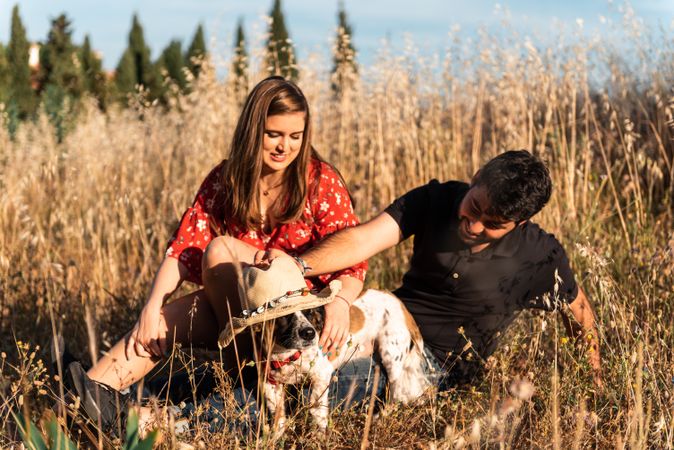 Happy couple with friendly cute dog resting outdoors